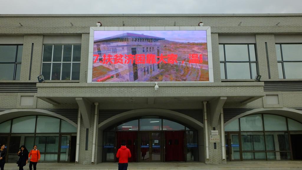 学院建筑墙体外液晶显示屏上的扶贫日宣传标语